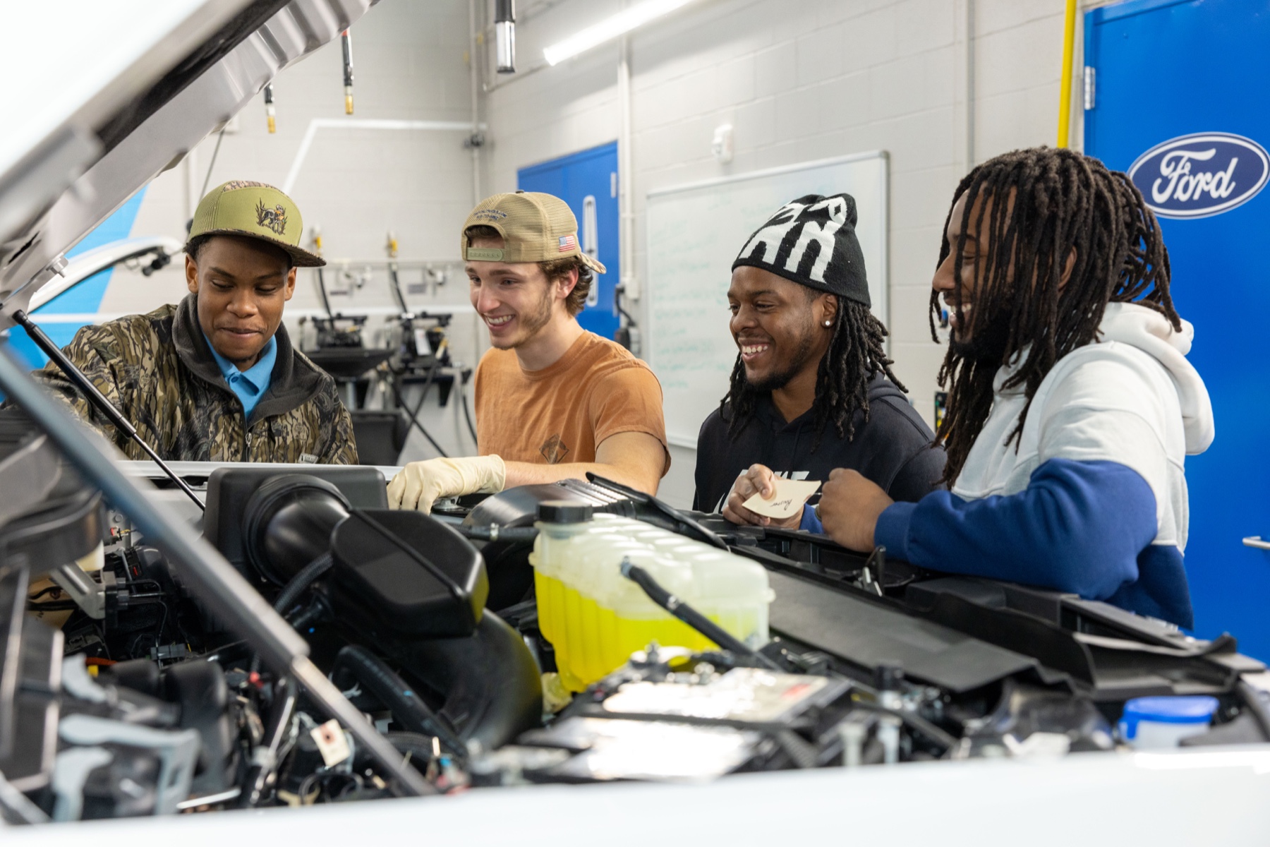 Wake Tech automotive students training together under the hood of a vehicle